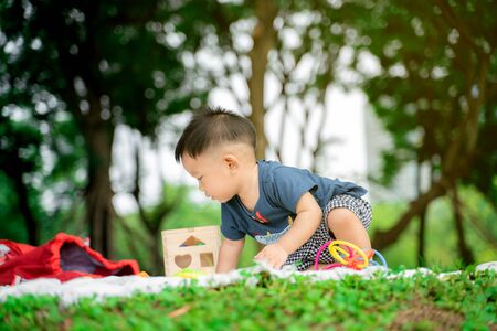 Toddler baby boy sitting in city green park playing toy weekend recreationの写真素材