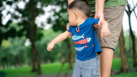 Adorable toddler asian boy walking in park by grandmather hand outdoor activity