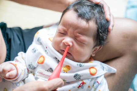 Father suck the snot from baby boy, Infant has runny noseの写真素材
