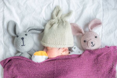 Cute infant baby boy sleeping on white blanket with teddy dollの写真素材