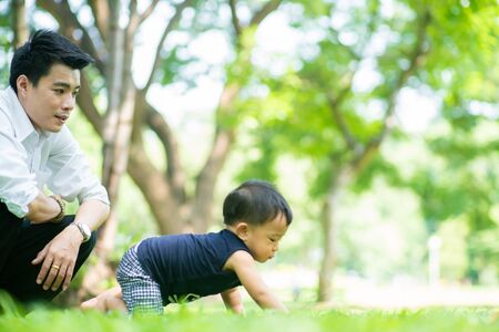 Adorable toddler baby boy playing toy in city park with father, Boy in natureの写真素材
