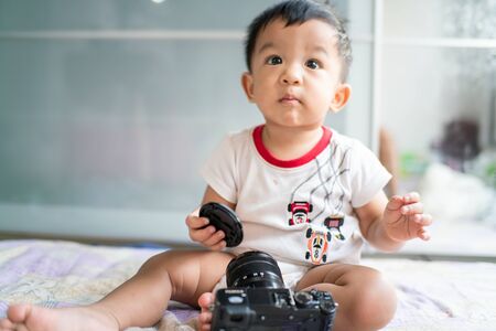 Adorable baby boy playing with camera in cozy roomの写真素材