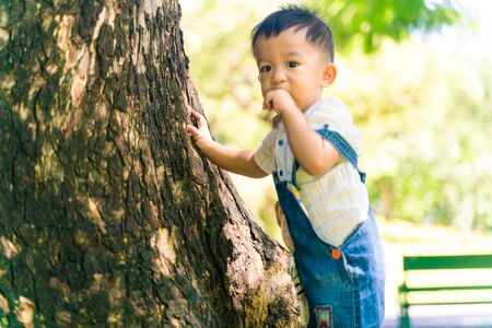 Smiling adorable baby boy sitting in city green park playing with toy baby in natureの写真素材