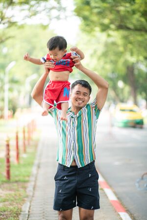 Baby boy playing with dad in green public morning park, Funny boy happyの写真素材