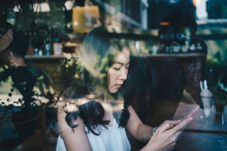 Business asian women use smartphone sitting in coffee shop day light