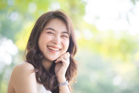 Portrait of smiling beautiful asian women in park morning light with bokeh half body portraitの写真素材