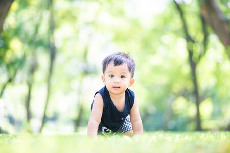 Adorable baby boy playing on green meadow city park, Funny. boyの写真素材