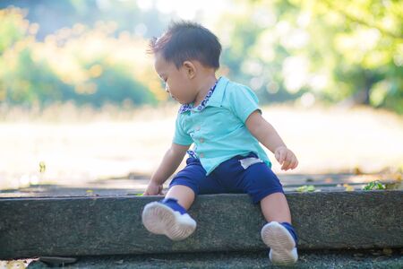 Adorable smart baby boy playing in city green park, Asian boyの写真素材