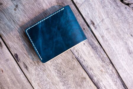 Leather navy blue with white cream wallet handmade working on wood background, Genuine vegetable...