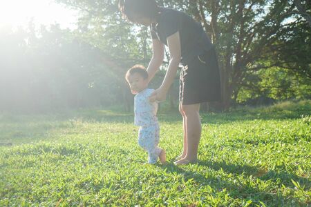 Adorable little baby boy first walking on green grass morning sunny lightの写真素材