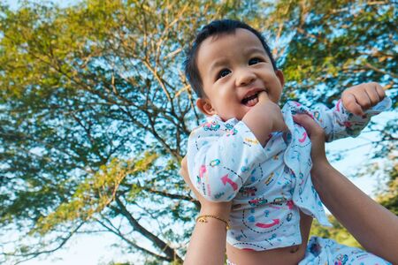 Infant baby boy hold by mom in park morning light healthy life