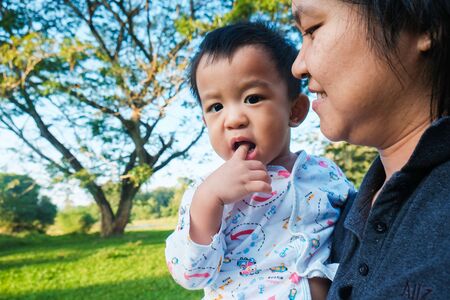 Infant baby boy hold by mom in park morning light healthy life