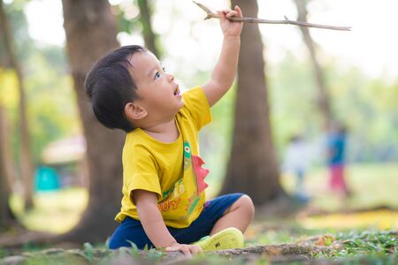 Adorable baby boy playing ujnder tree in city park sunset light nature in cityの写真素材
