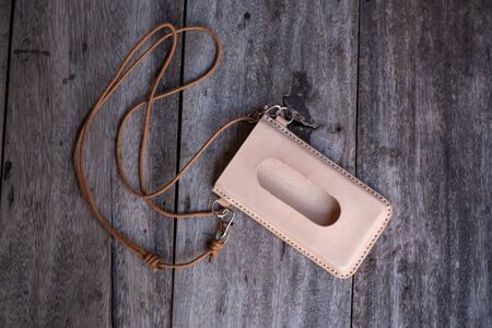 Genuine leather cell phone cover case neck on wood background