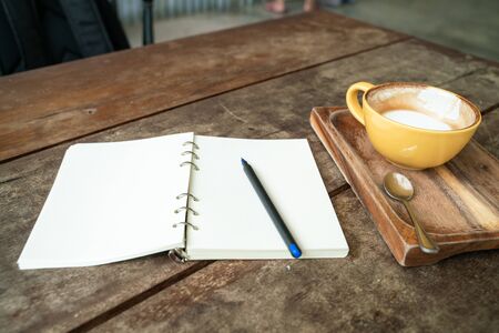 Hot latte coffee cup on wood table with blank notebook, Writer concept