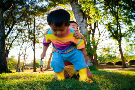 Happy kid boy walking in the park playing outdoor on grass in summer sunset lightの写真素材