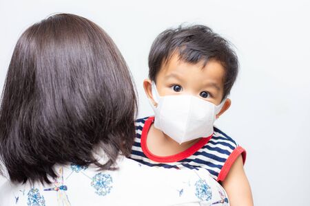 Asian mother carry baby boy wear mask protect pm2.5 and COVID-19 outbreak on white backgroundの写真素材