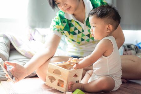 Baby boy playing toy with mother in living room children development
