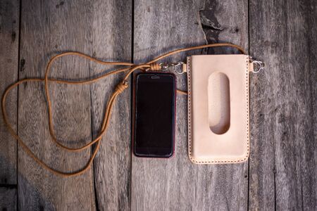 Genuine leather cell phone cover case neck on wood background