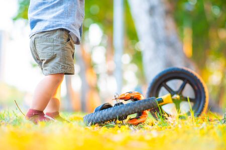 Asian boy falling balance bike accident on road in park tree forest outdoor activity