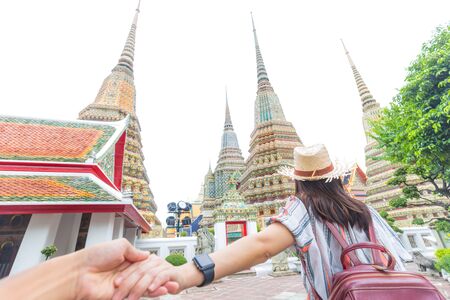 Tourist asian women leading man hand rear view go to buddhist temple, Couple travelの写真素材