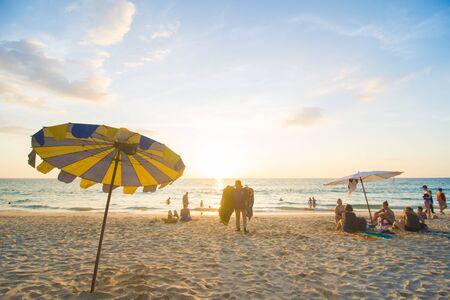 Blurred group of people enjoying sunset on sea beach with umbrella vacationの写真素材