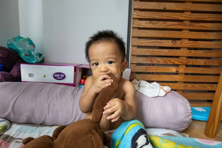 Adorable baby boy nervously expression biting doll and toy first tooth growingの写真素材
