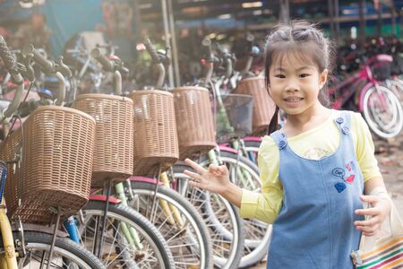Adorable little girl enjoying with bike in public city park, Happy girlの写真素材
