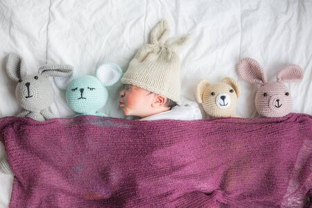 Sleepin of infant baby boy with many doll on white blanket newborn conceptの写真素材
