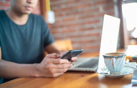 Business man hand use smartphone while drinking hot latte coffe in cafe cloe up on hand