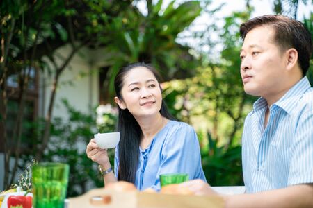 Elder retirement couple drinking coffe and talking in park, Asian coupleの写真素材