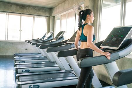 Smart asian women running on treadmill in modern gym working out