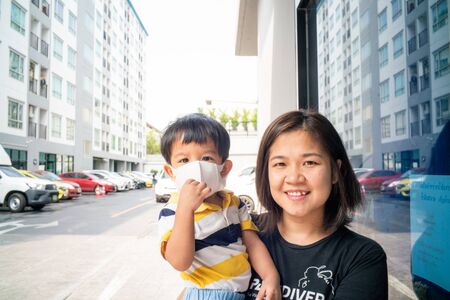 Asian cute boy and mother wearing N95 mask outdoor city building protect Coronavirus and Air pollution pm2.5. Awareness virus spread conceptの写真素材