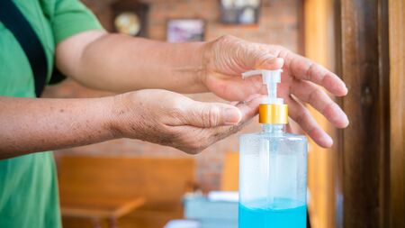 Coronavirus old women hand sanitizer sanitiser gel for clean hands hygiene corona virus spread prevention. Woman using alcohol to washing hands.の写真素材