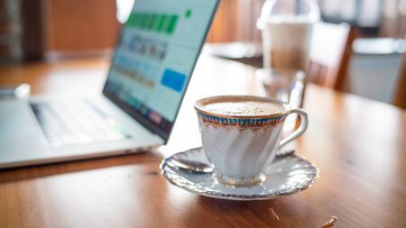 Hot aroma cappuccino coffee cup on wooden table work from home with laptop, Home business WFH...