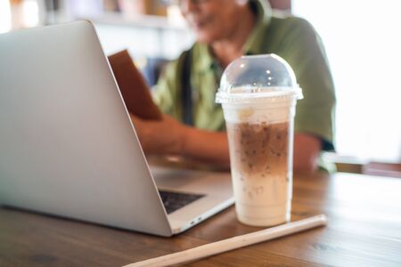 Senior asian women use smartphone with laptop sitting in coffee shop business women workingの写真素材