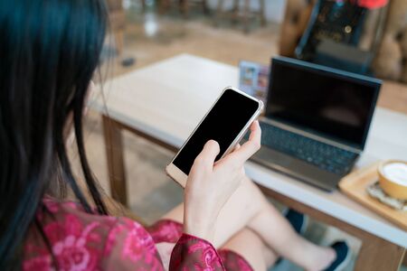 Beautiful asian entrepreneur use smartphone with laptop sitting in coffee shop, Business women