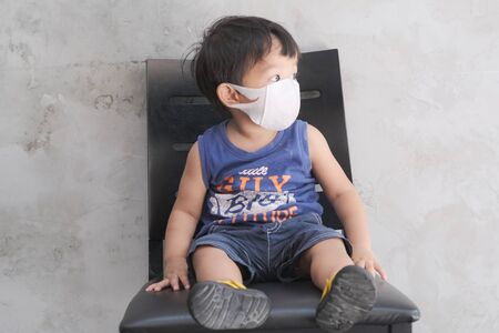 Little boy wear white mask protect Pm2.5 amd covid 19 sitting in cafe, Healthy conceptの写真素材
