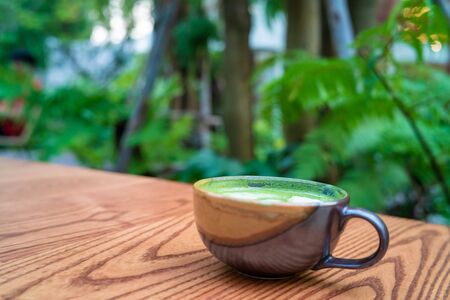 Hot matcha green tea l;atte art on wooden table hot cafein drinkの写真素材