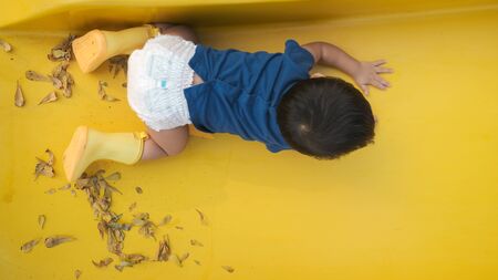 Adorable child boy playing on outdoor slider in park hgome garden nature learnningの写真素材