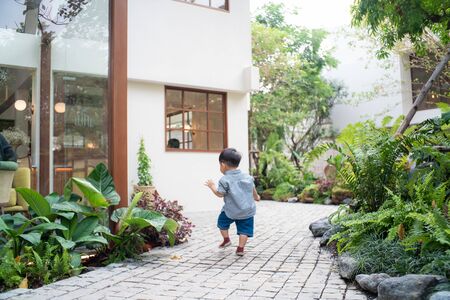 Adorable baby boy toddler walking in garden home green tree boy in natureの写真素材