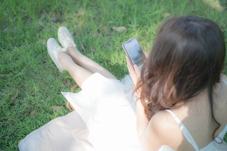 Beautiful asian woman using mobile smart phone internet connection blank screen view in the park.の写真素材