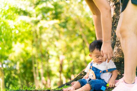Happy little boy playin on green grass in city public park under tree sun light with bokeh blurredの写真素材
