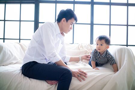 Office business father playing with little boy after working done on sofa in cozy roomの写真素材