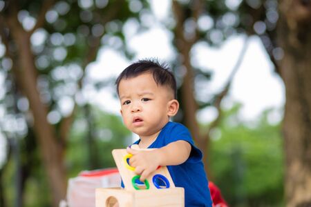 Adorable baby boy playing colorful toy on green grass in city park outdoor activityの写真素材