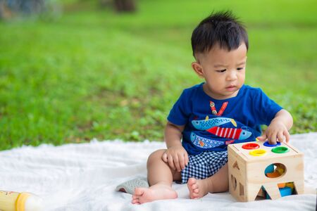 Adorable baby boy playing colorful toy on green grass in city park outdoor activityの写真素材