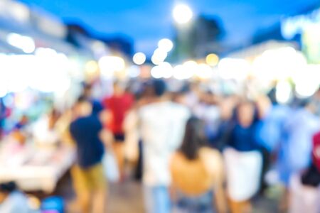 Group of blurred people shopping in outdoor market with light bokehの写真素材