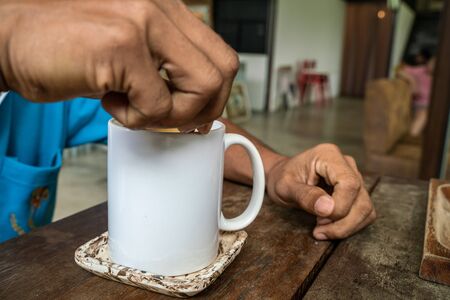 Man hand stir americano coffee cup on wood table in cafe shopの写真素材
