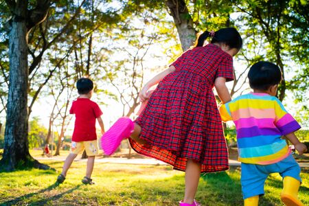 Group of happy children playing on green grass activity sunset light outdoors in spring park