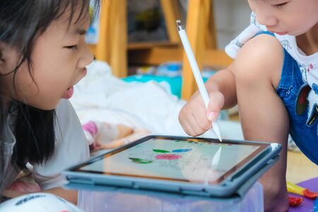 Children drawing image with tablet computer pen while playing in house children learnning art educationの写真素材